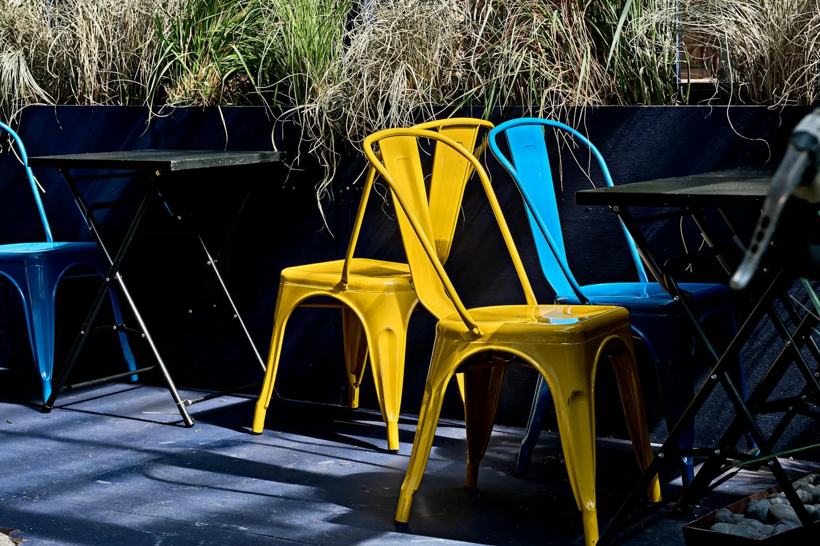 Yellow and blue powder-coated steel garden chairs on an outdoor patio deck