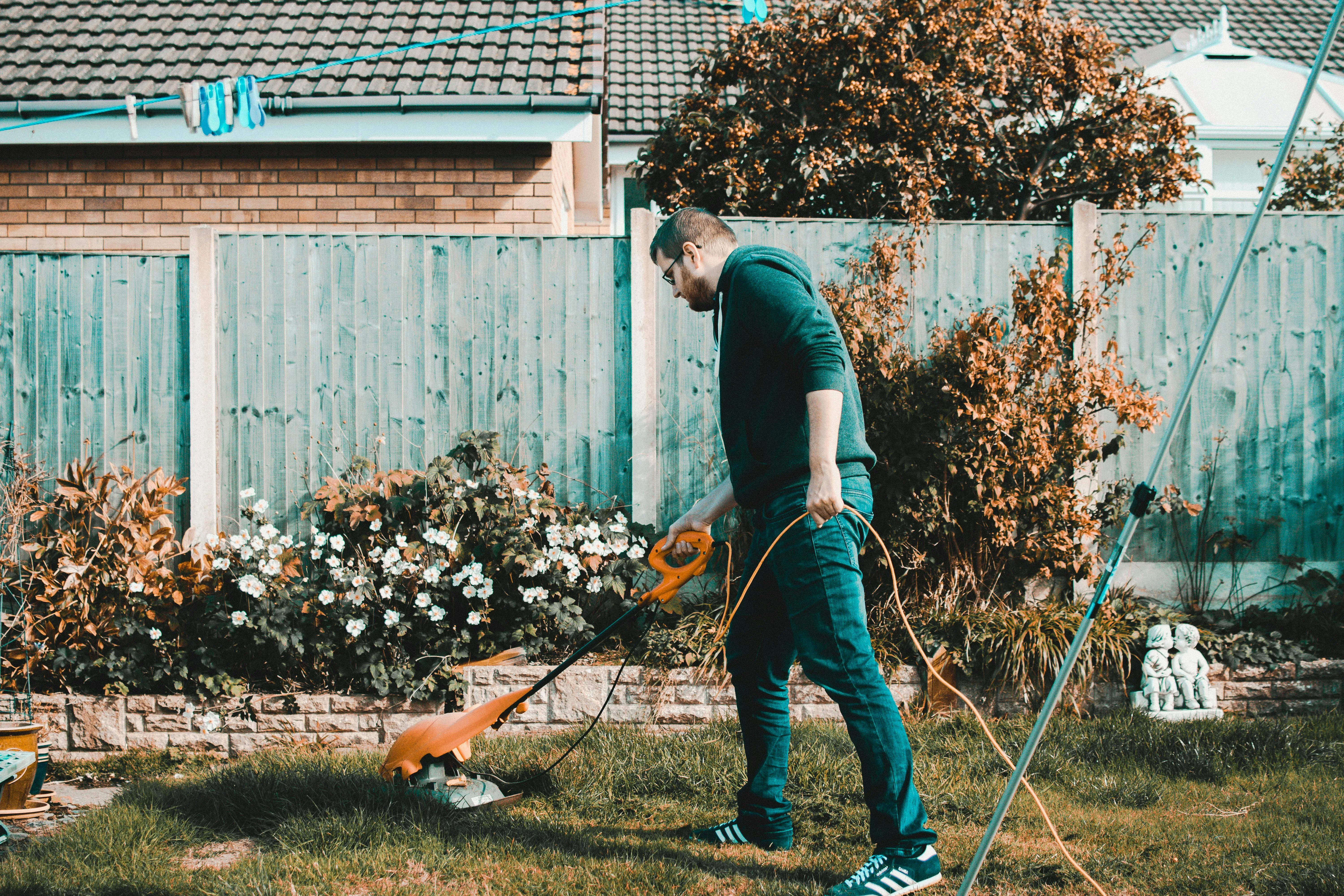 Person mowing a small garden with an electric push lawnmower