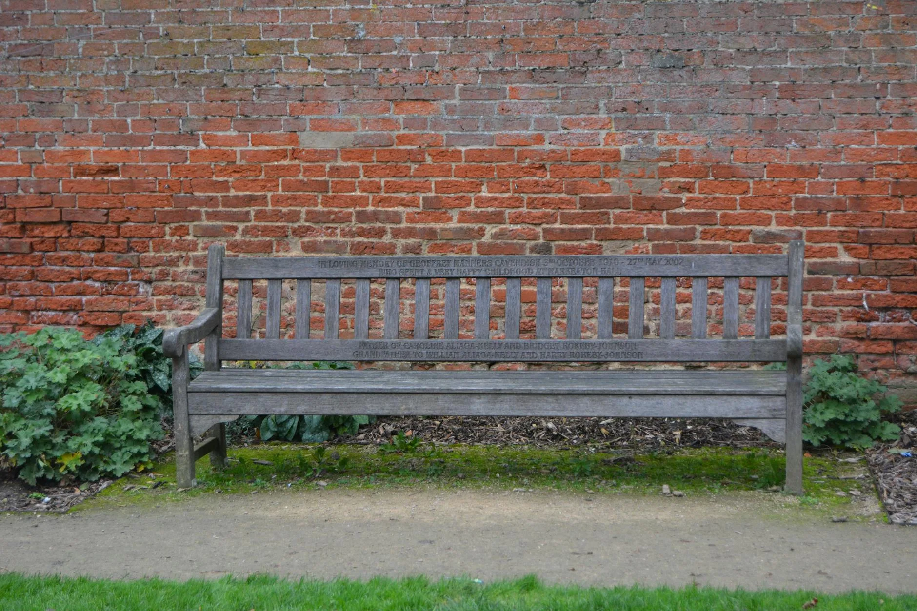 Weathered teak garden bench in a lush green garden setting