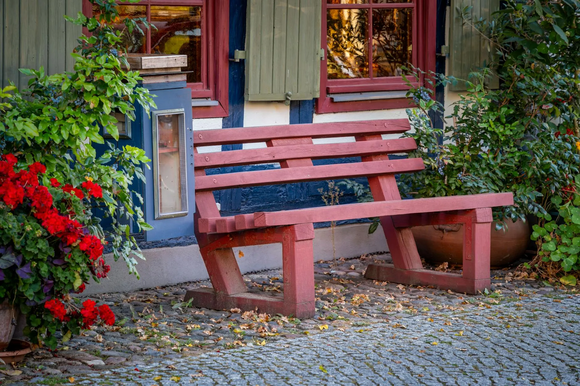 Garden bench surrounded by flowers beside a charming house