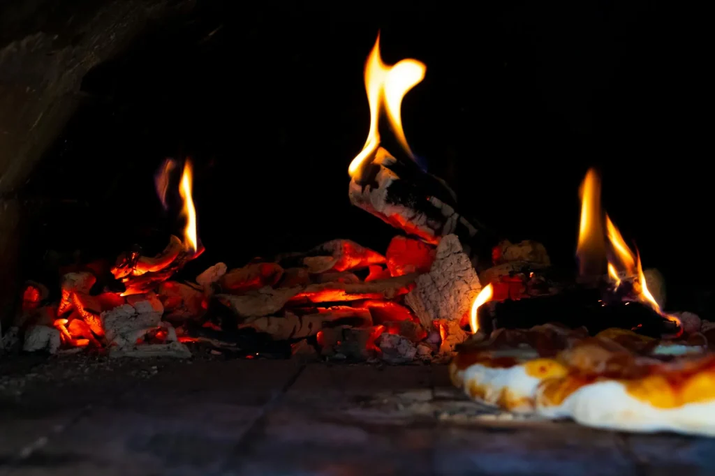 Outdoor pizza oven with fire burning in a garden setting