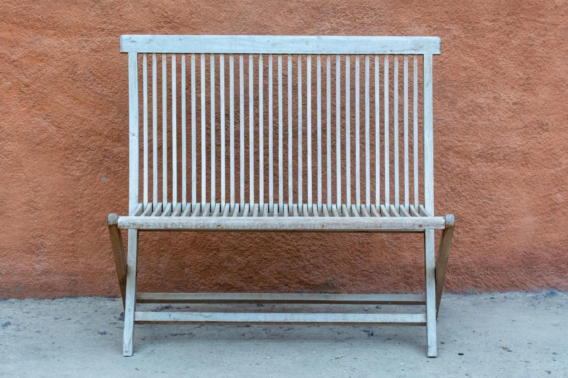 Teak wooden garden bench on a patio in afternoon sunlight