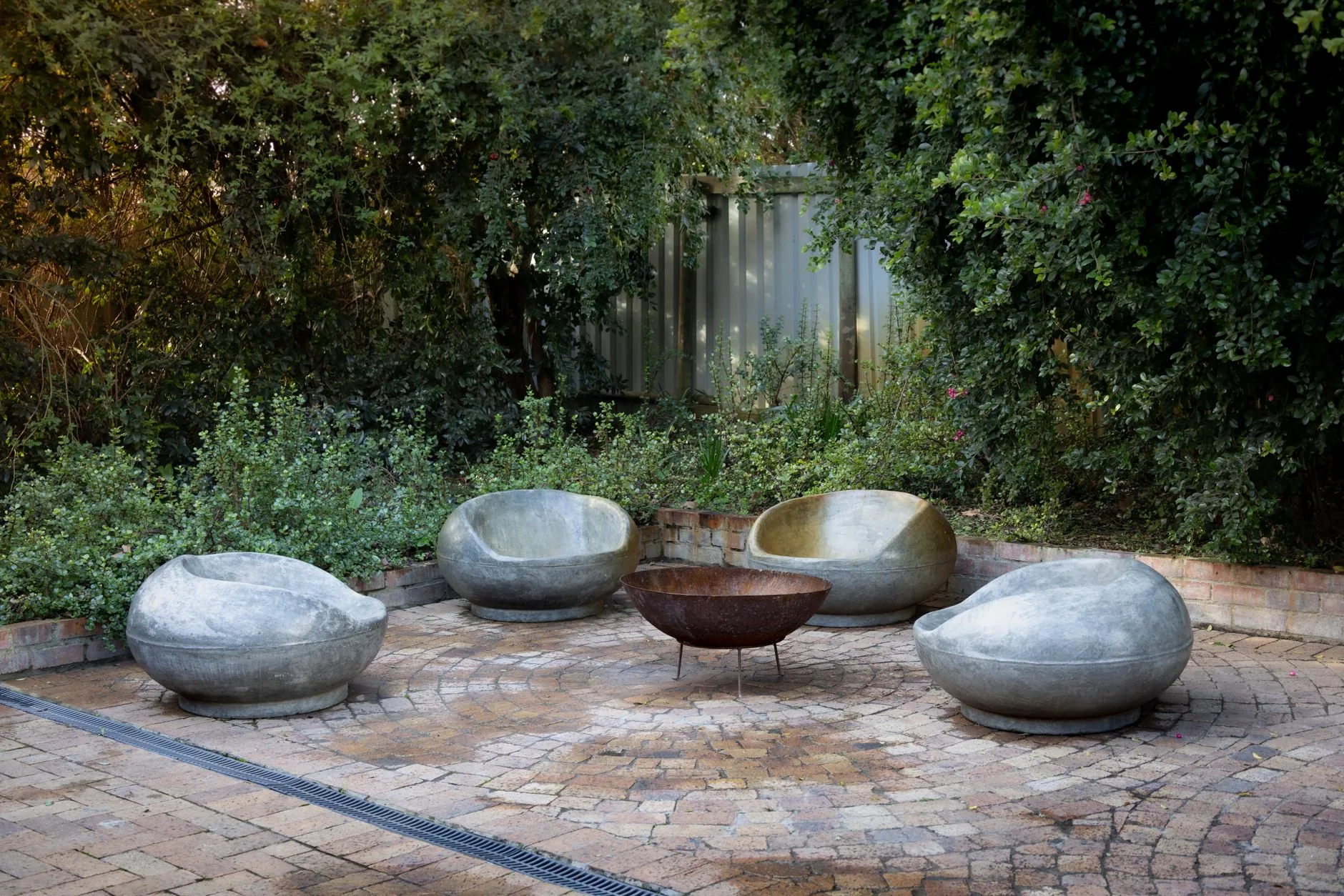 Fire pit set on stone patio with clear space from garden furniture