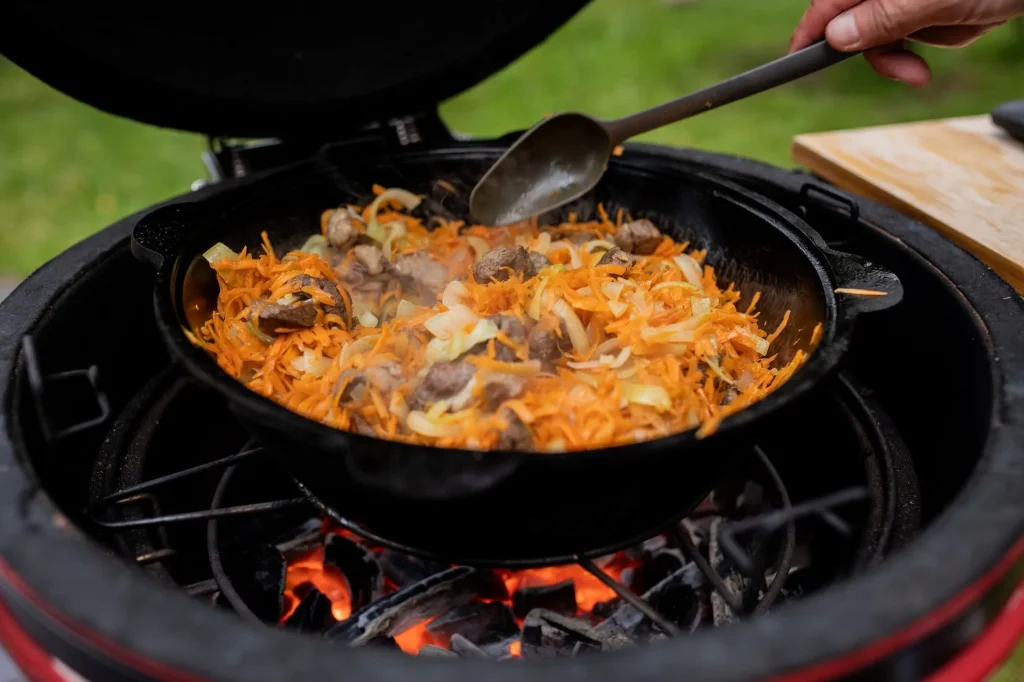 Red ceramic kamado barbecue set up on a garden patio