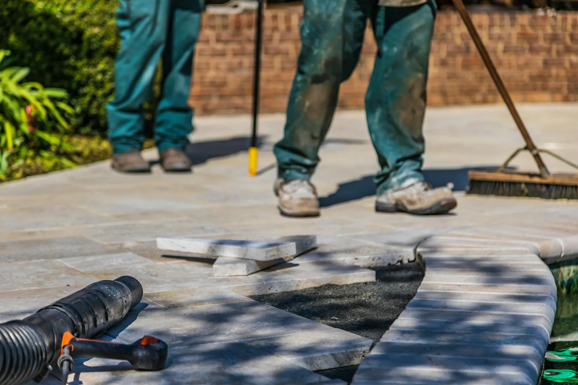 Workers laying paving slabs on a prepared patio base