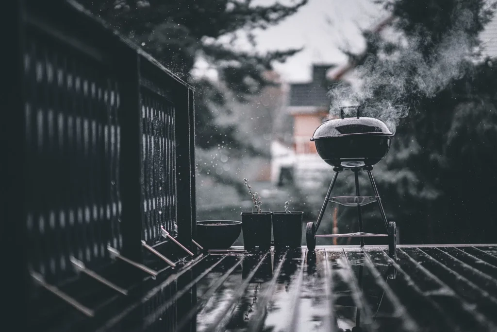 Black kettle-style charcoal barbecue set up on a garden patio