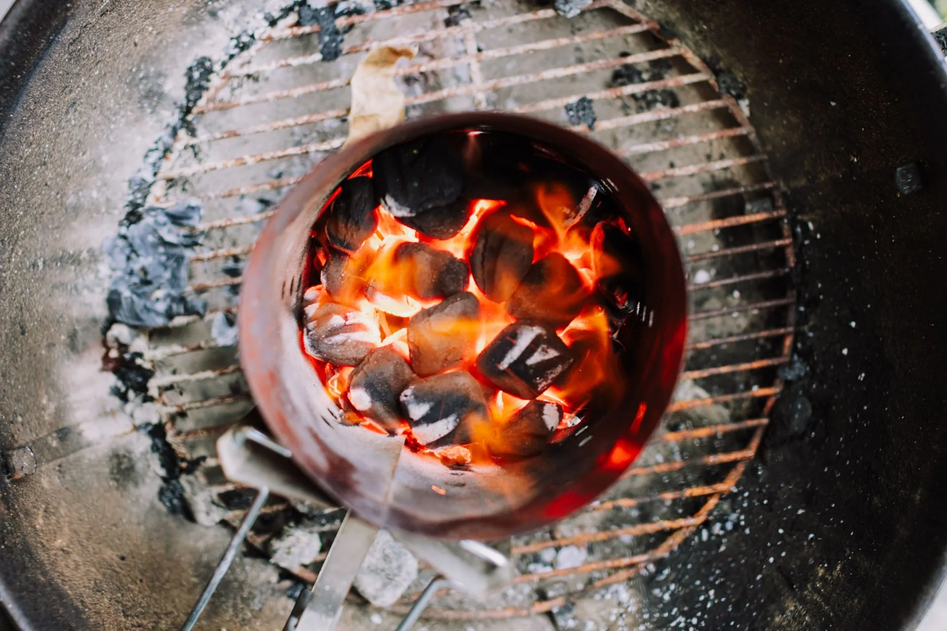 Charcoal barbecue tools and fuel setup beside an outdoor grill