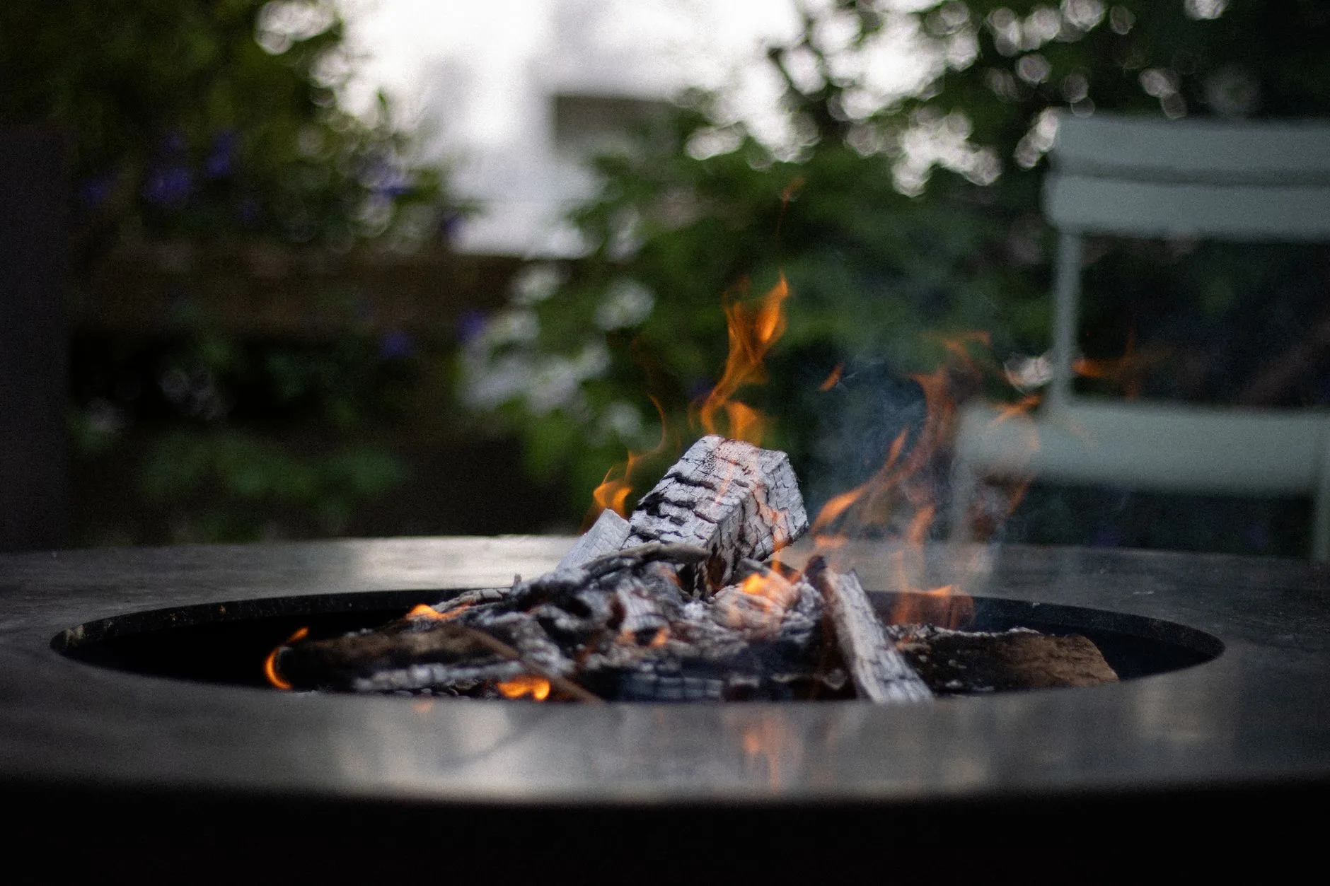 Wood-burning fire pit with flames on a garden patio